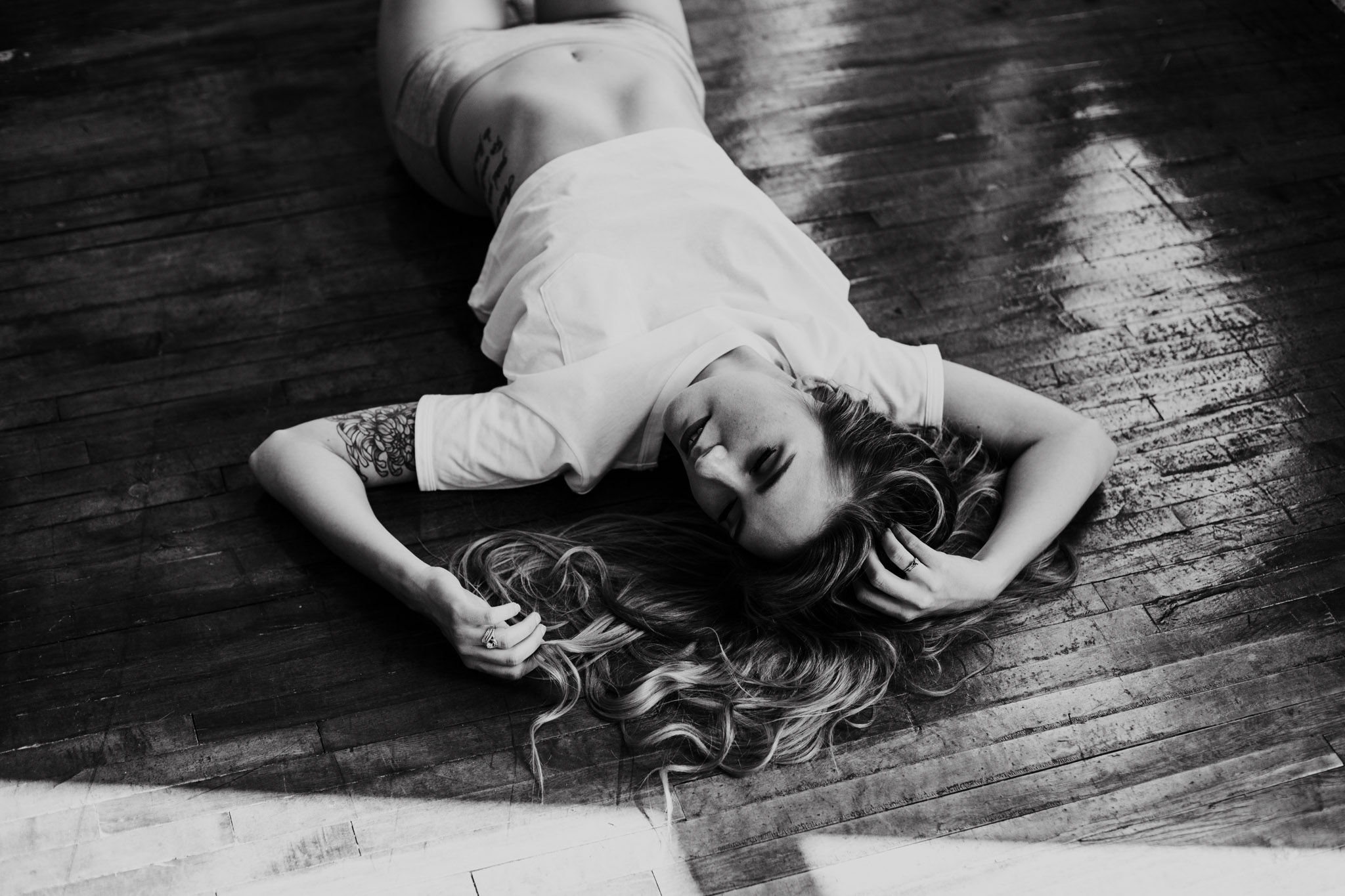 blonde boudoir model laying on wooden floor in Juniper Loft - Black and white